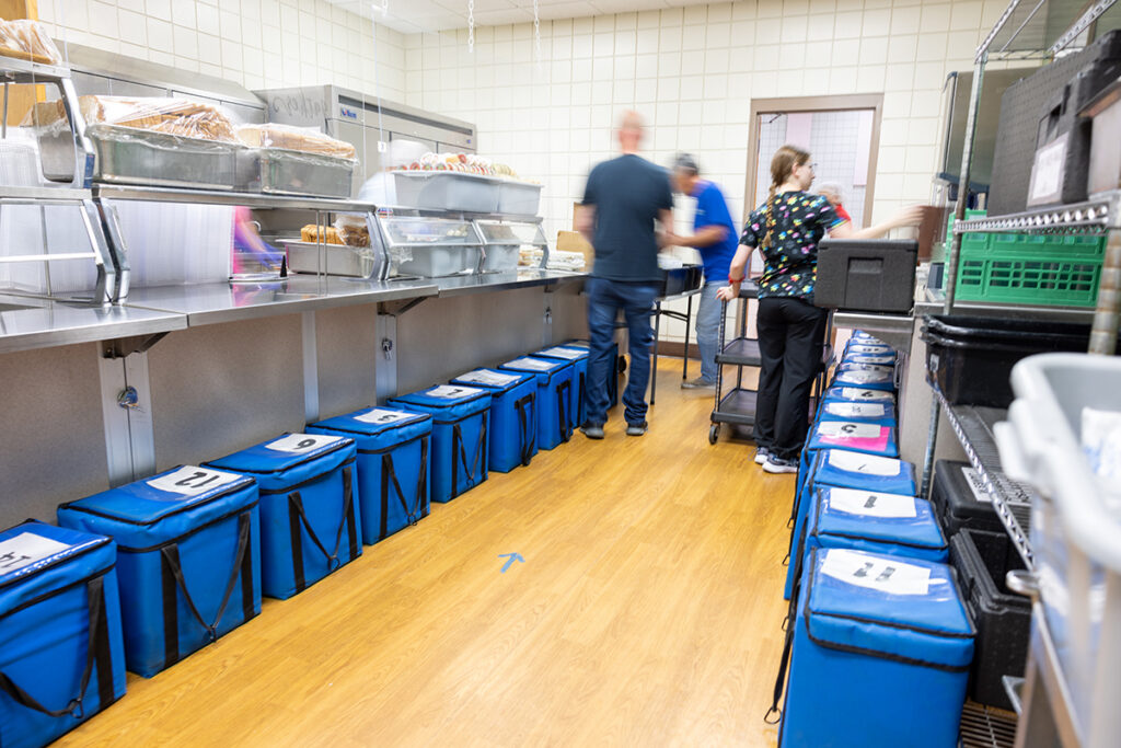A busy industrial kitchen shows people preparing food