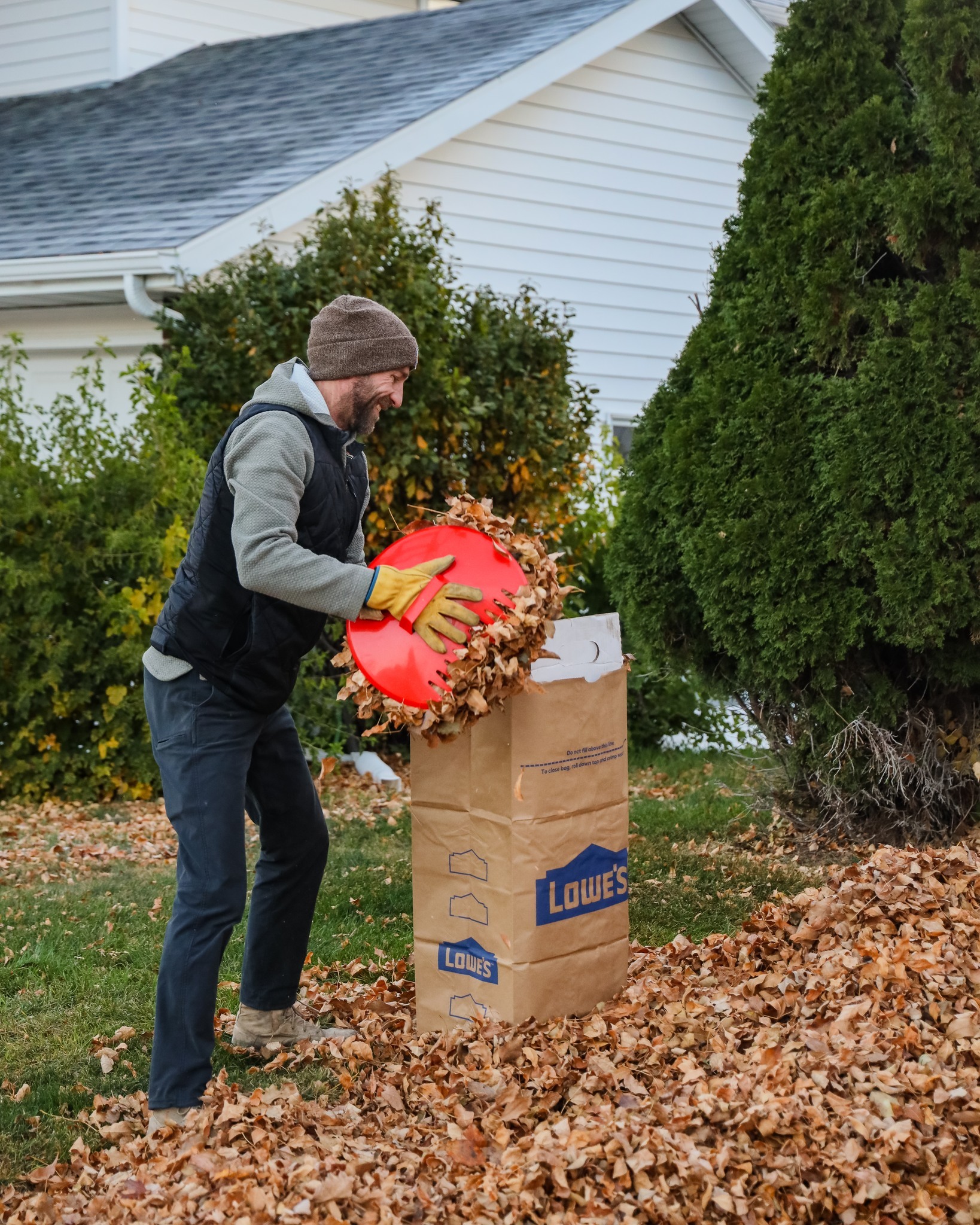 A man puts leaves into a yard waste bag.